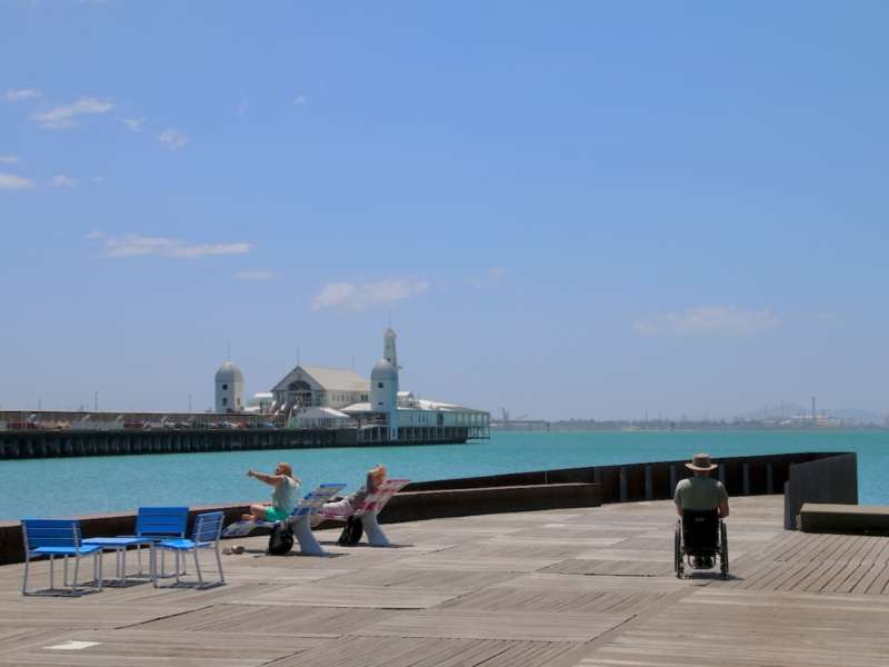 A picture depicting blue water and building in the background and a wheelchair user on the western and eastern accessible walk