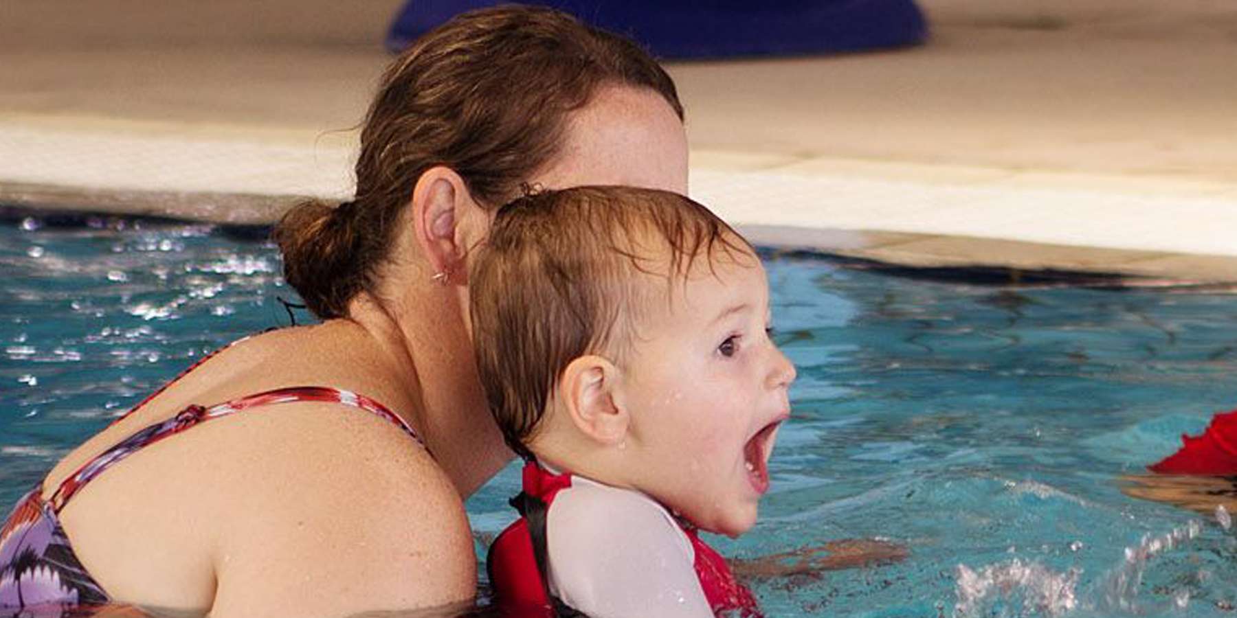 A woman and a child are enjoying time together in a swimming pool, showcasing a joyful and playful atmosphere.