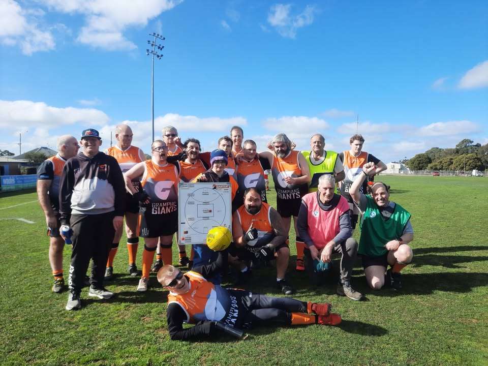 A group of people wearing football jerseys with the coaches.