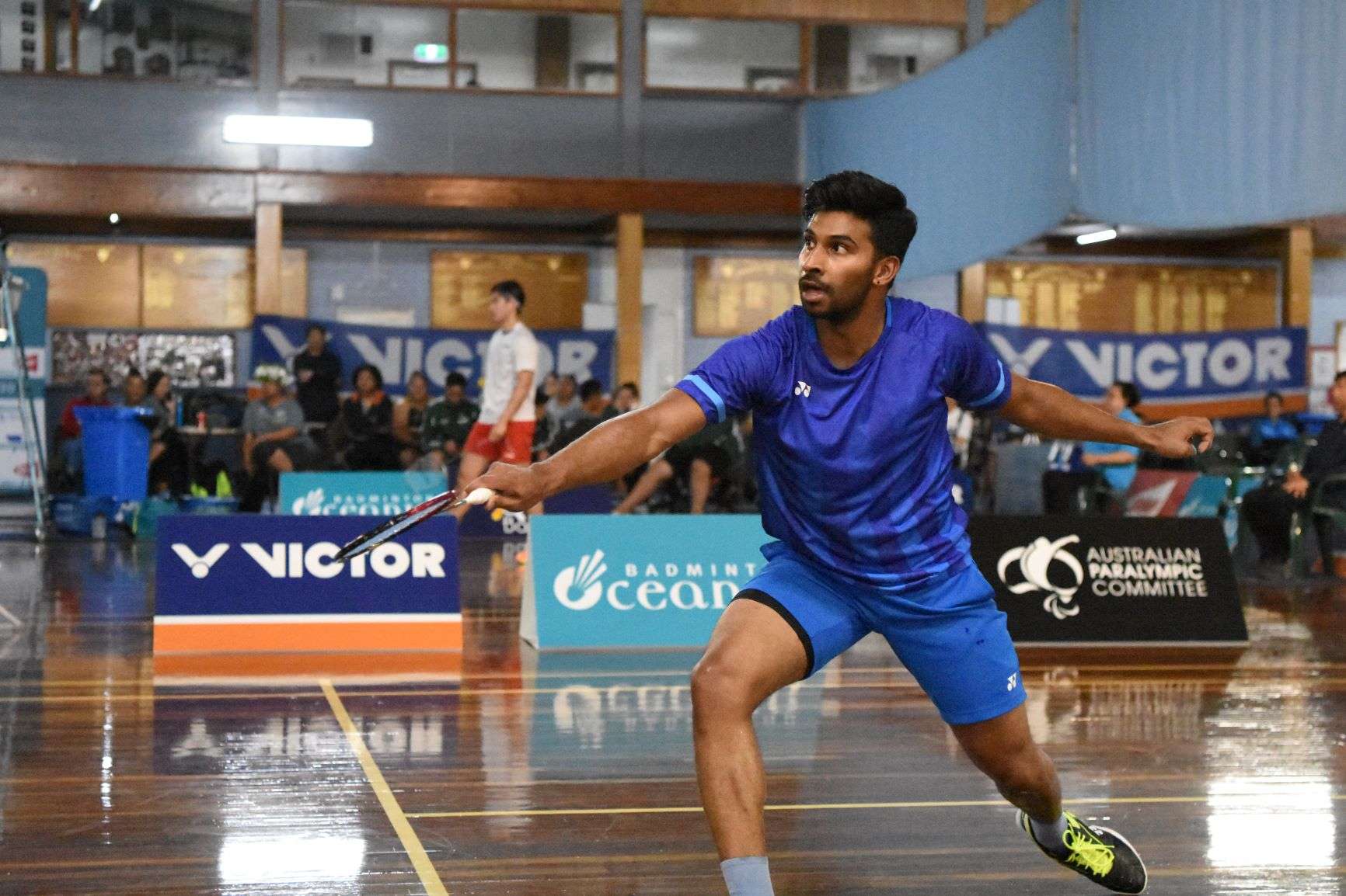 A man on a court playing badminton.