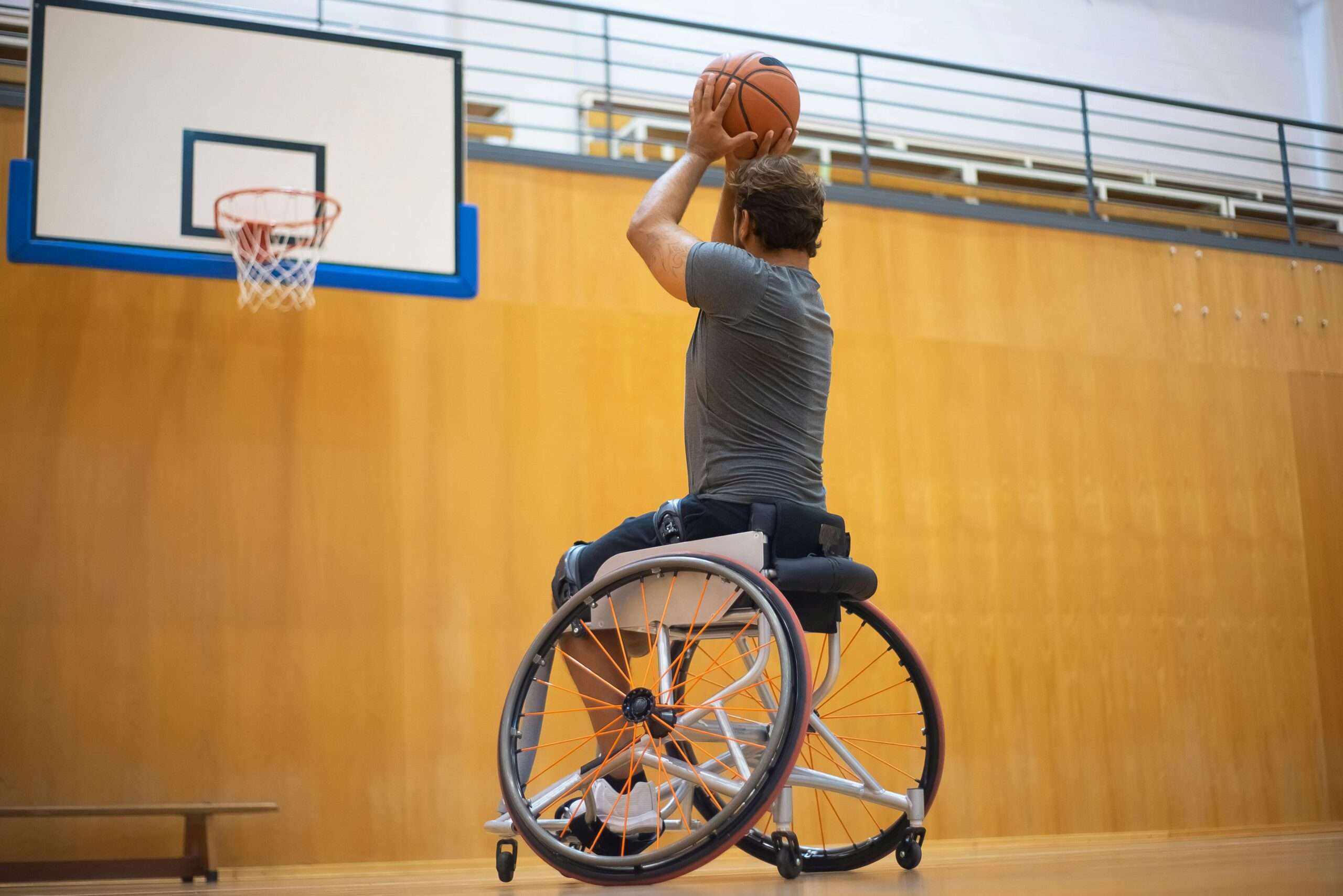 Photo of a Man in a Gray Shirt Playing Basketball in a wheelchair