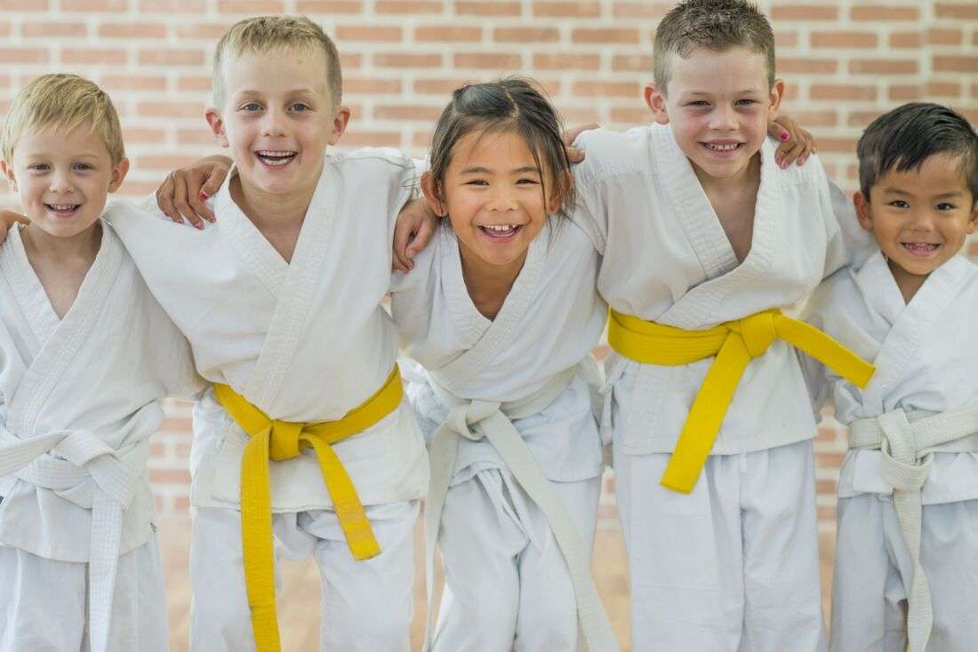 A group of children wearing karate uniforms with yellow belts.