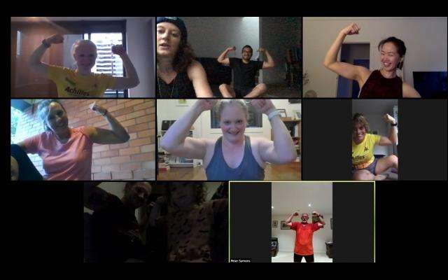 A grid of nine participants flexing their arms in a virtual fitness class, showcasing camaraderie and strength through video chat.