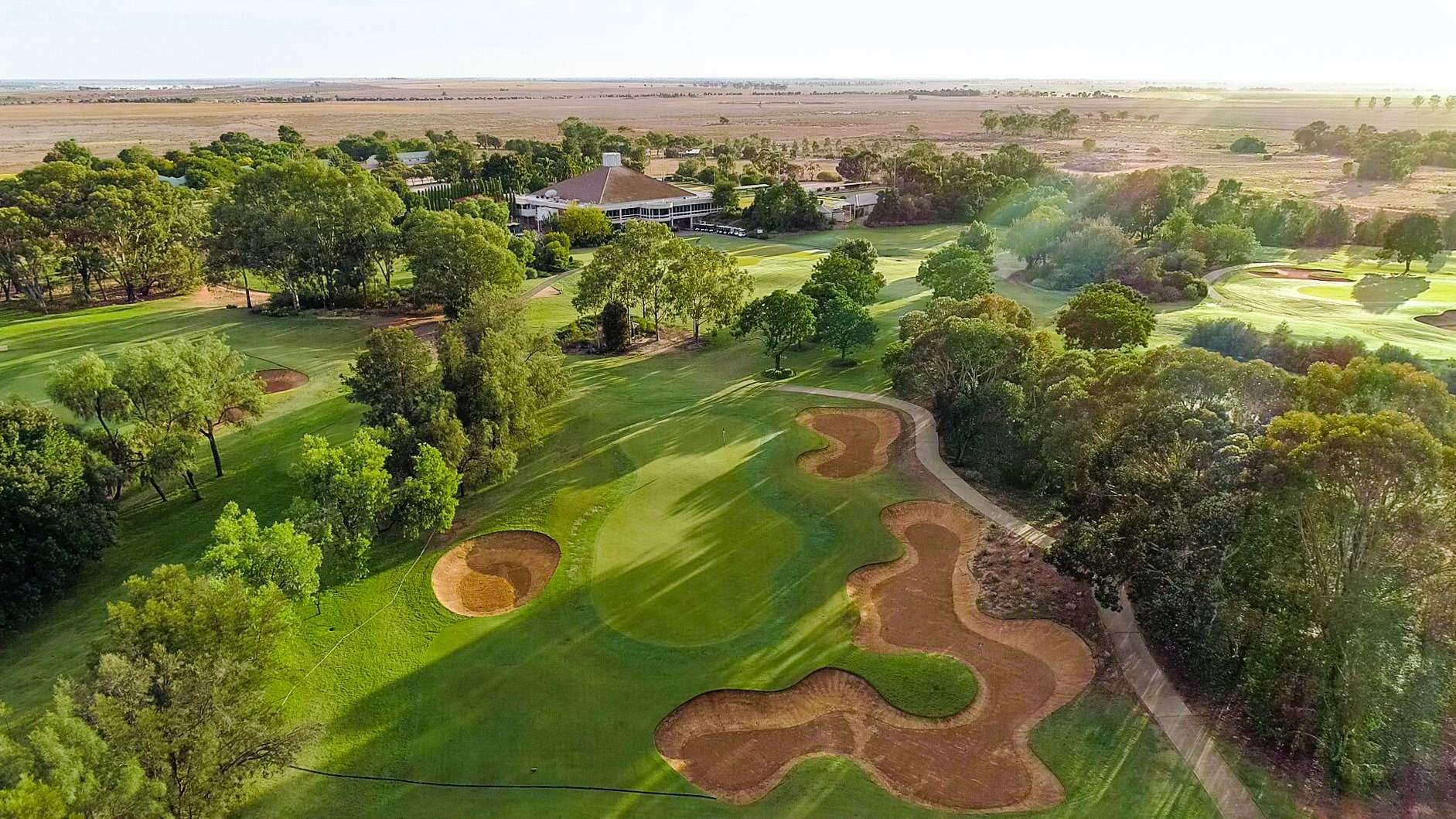 A large green golf course surrounded by trees.
