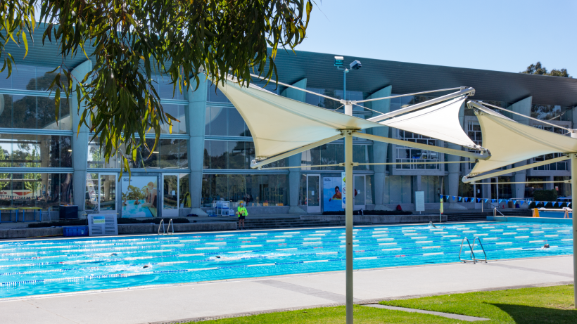An indoor inground level swimming pool with multiple lanes divided by ropes.